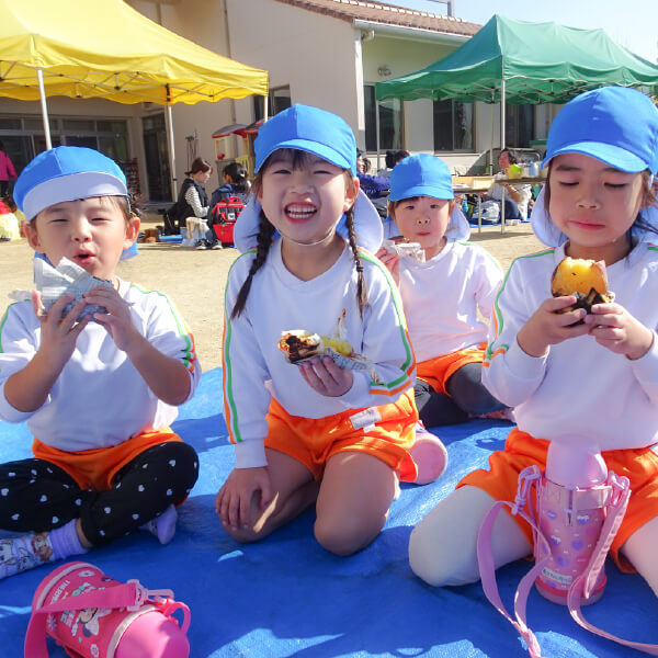 園庭でおやつを食べる園児たち