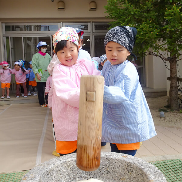 臼で餅つきを体験する園児たち