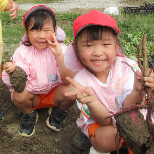 収穫した野菜を手にする園児たち