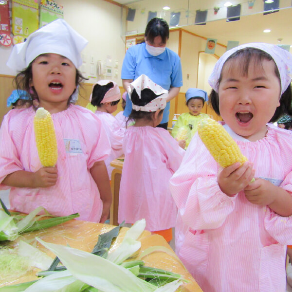 とうもろこしの皮むきをする園児たち