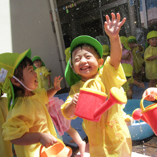 じょうろで水遊びをする園児たち