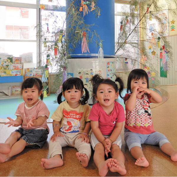七夕飾りの前に座る園児たち