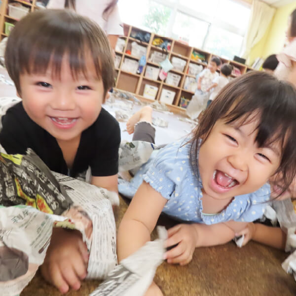 新聞紙遊びで笑顔の園児たち